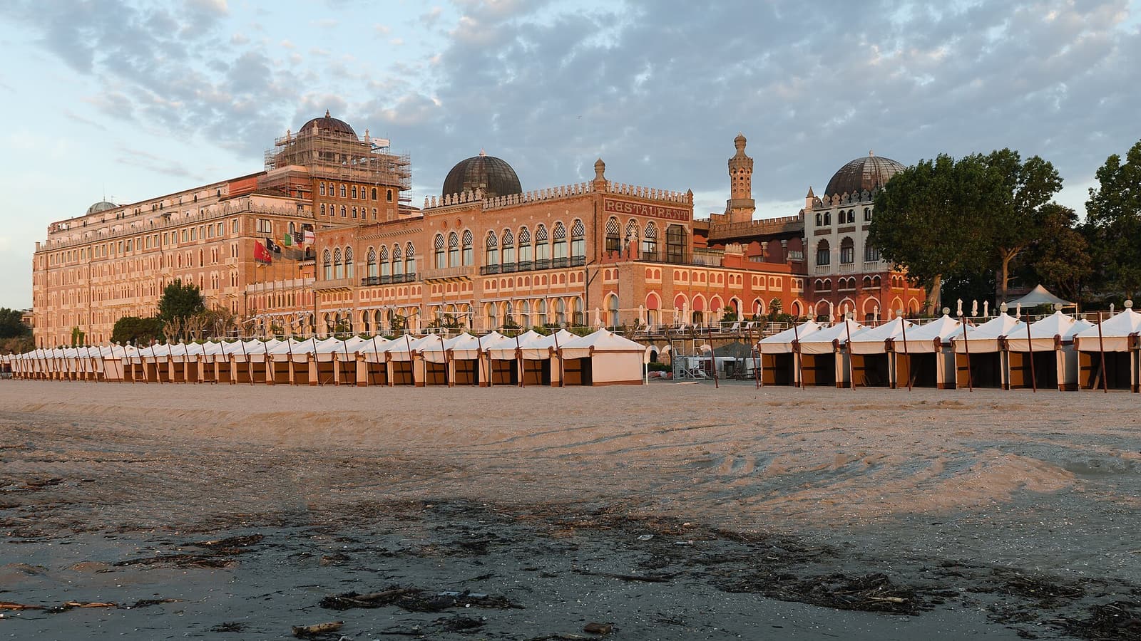 Das neomaurische Hotel Excelsior vom Strand aus mit Kabinenreihen im Morgenlicht