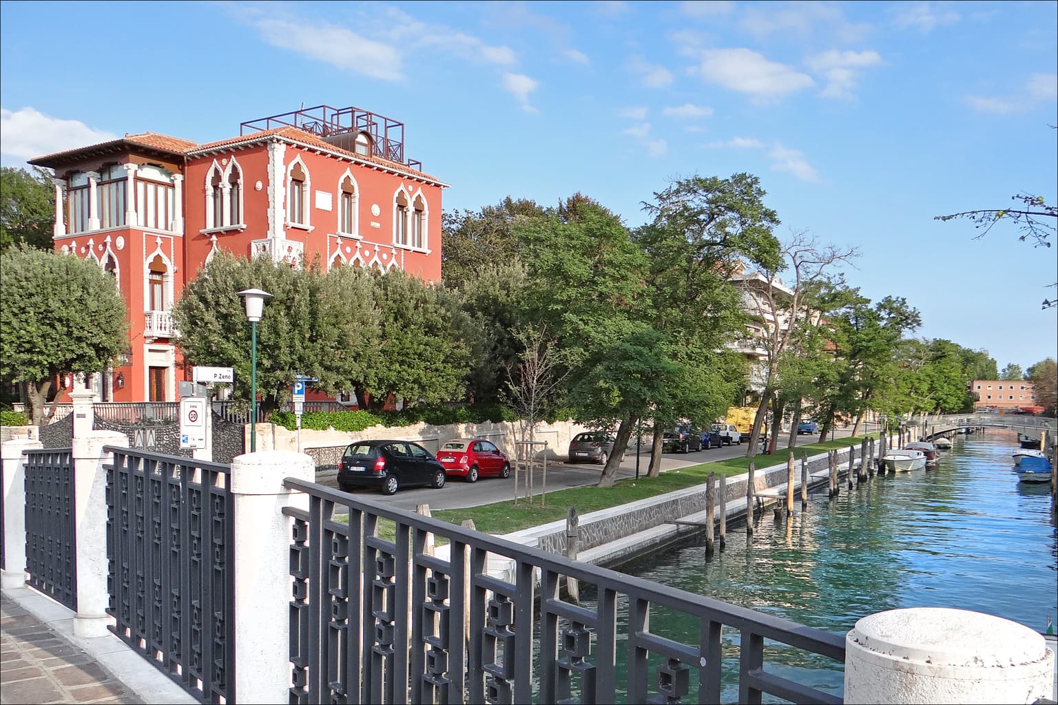 Eine rote Villa im venezianisch-gotischen Stil an einem Kanal auf dem Lido