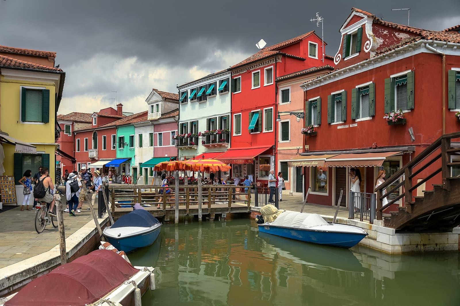 Bunt gestrichene Häuser spiegeln sich in einem Kanal auf Burano