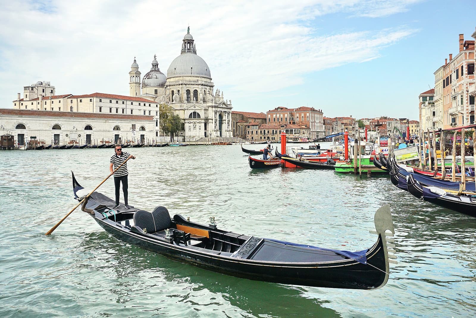 Ein Gondoliere rudert über den Canal Grande vor der Kirche Santa Maria della Salute